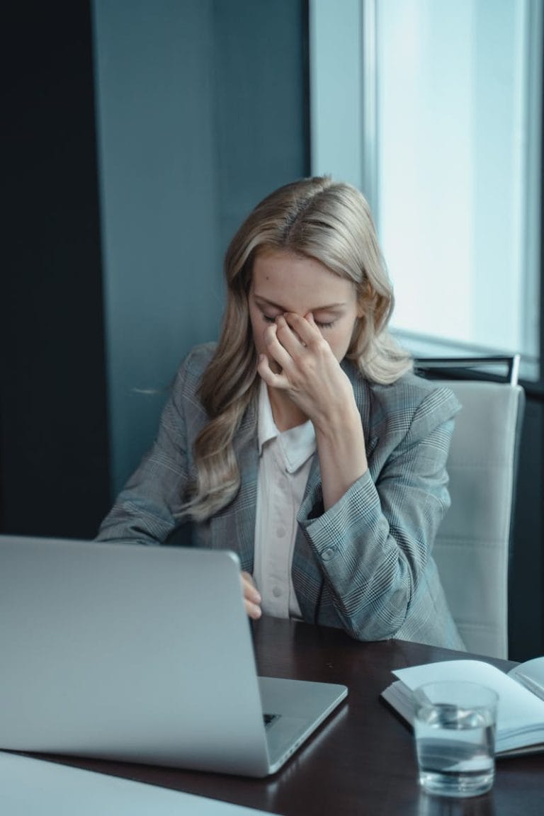 Businesswoman showing stress at her desk with a laptop, highlighting work pressure.